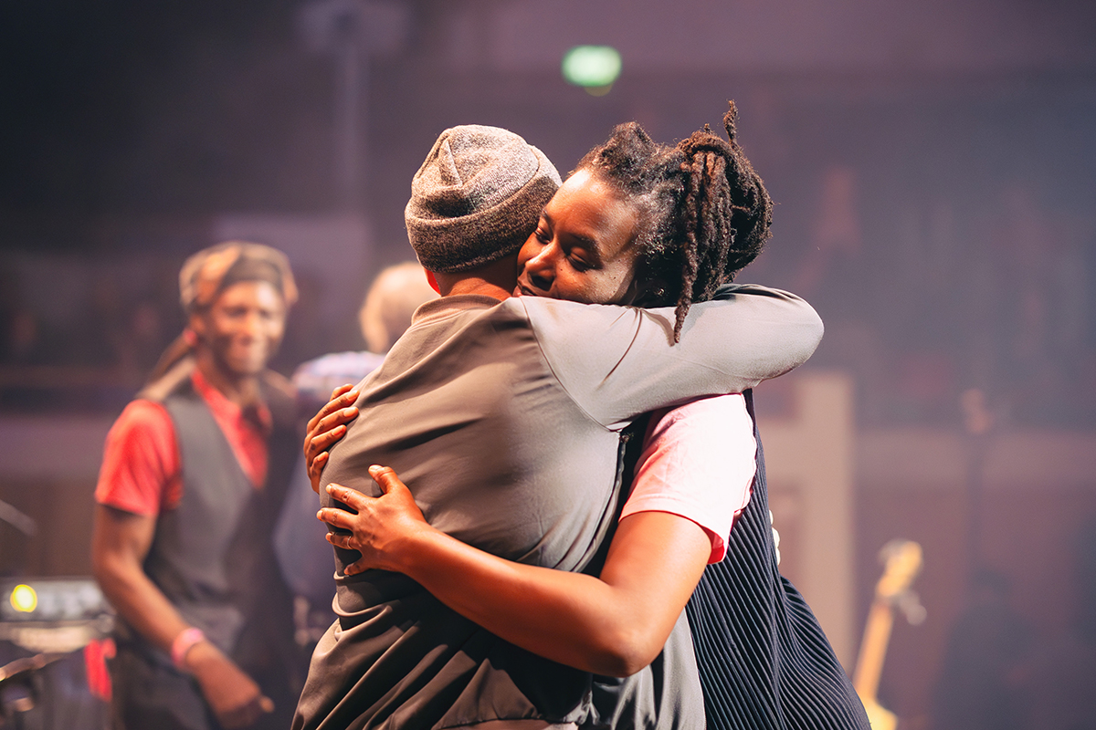 two members of The Harvest Time Project hugging on stage 